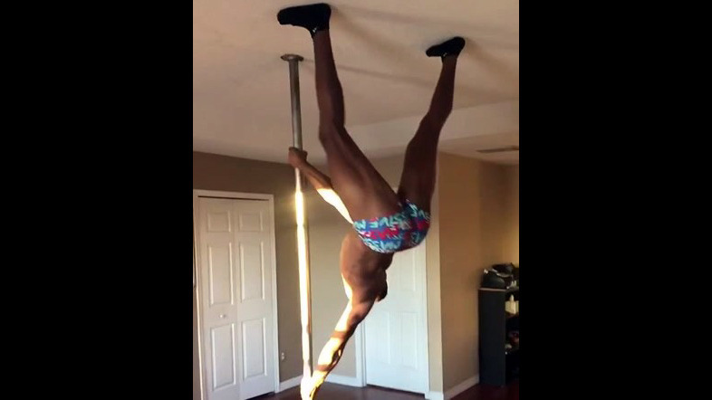 Ebony male stripper flipping on a pole.